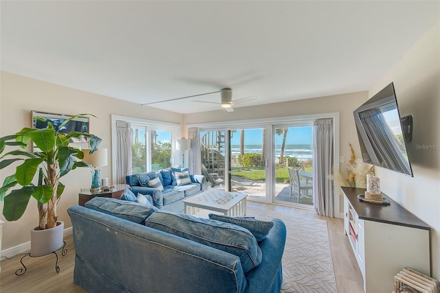 living area with a healthy amount of sunlight, light wood-style floors, baseboards, and a ceiling fan