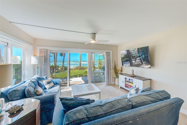 living area with ceiling fan, light wood finished floors, a wealth of natural light, and baseboards