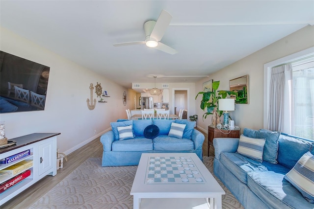 living area featuring baseboards, a ceiling fan, and light wood-style floors