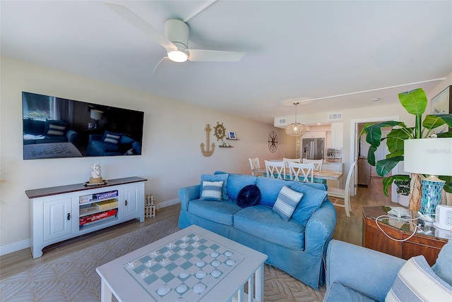 living area with baseboards, light wood finished floors, visible vents, and a ceiling fan