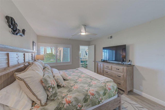 bedroom with ceiling fan, light wood finished floors, visible vents, and baseboards