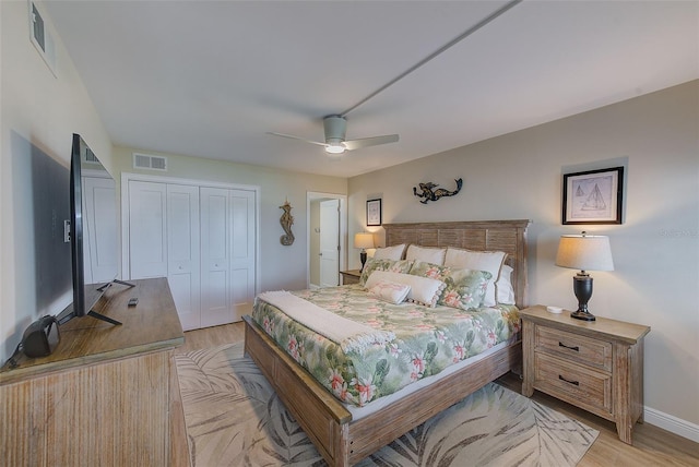 bedroom with light wood-type flooring, a closet, visible vents, and ceiling fan