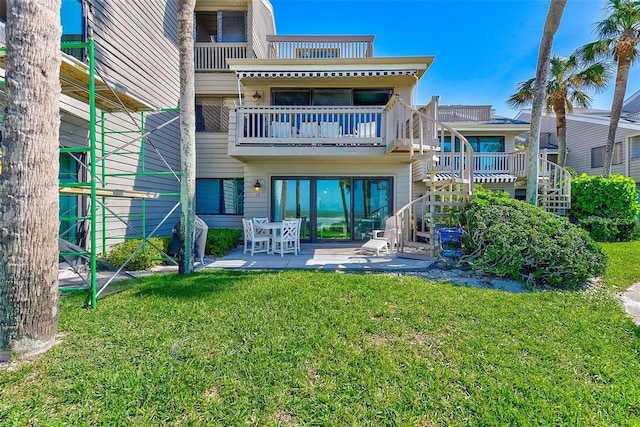 back of house with a balcony, a patio area, stairway, and a yard