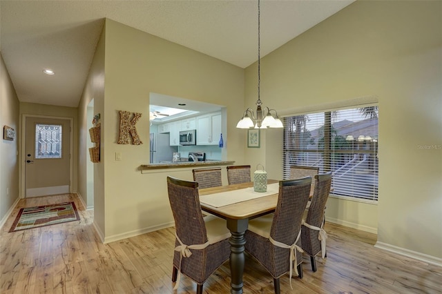 dining room featuring light wood-style flooring, an inviting chandelier, and baseboards