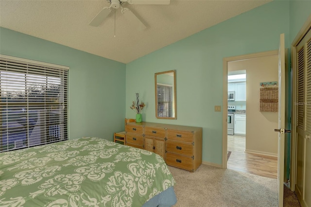 bedroom with a ceiling fan, a textured ceiling, a closet, lofted ceiling, and light colored carpet