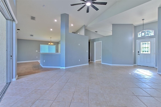 unfurnished living room featuring ceiling fan with notable chandelier, light tile patterned floors, and high vaulted ceiling