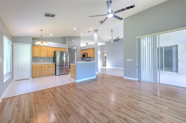 kitchen featuring appliances with stainless steel finishes, high vaulted ceiling, decorative light fixtures, and light hardwood / wood-style flooring