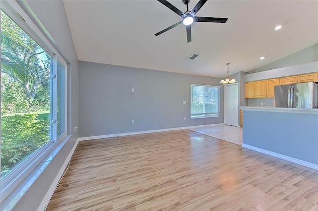 unfurnished living room with ceiling fan with notable chandelier, light wood-type flooring, and lofted ceiling