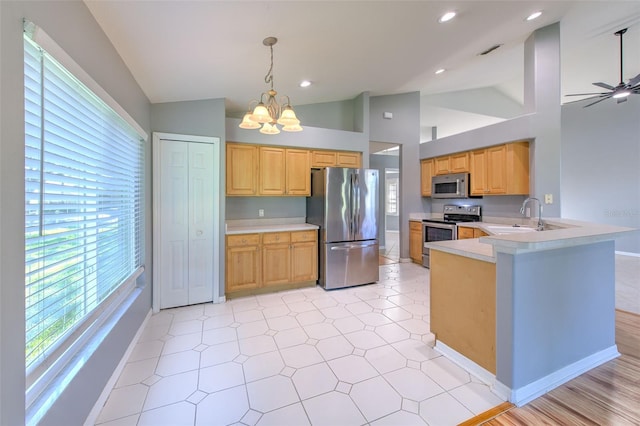 kitchen featuring kitchen peninsula, stainless steel appliances, vaulted ceiling, sink, and decorative light fixtures