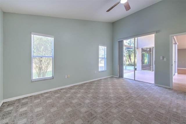 spare room with light carpet, lofted ceiling, ceiling fan, and a healthy amount of sunlight