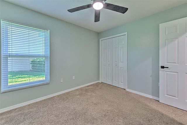 unfurnished bedroom featuring a closet, light colored carpet, and ceiling fan