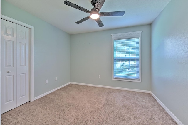 unfurnished bedroom with light carpet, a closet, and ceiling fan