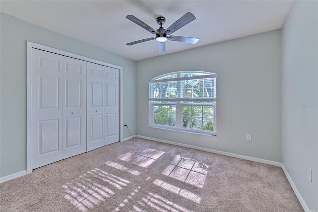 unfurnished bedroom with ceiling fan, light colored carpet, and a closet