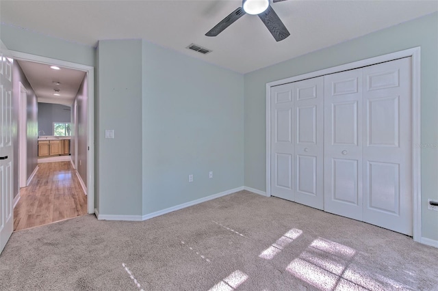 unfurnished bedroom featuring a closet, light colored carpet, and ceiling fan