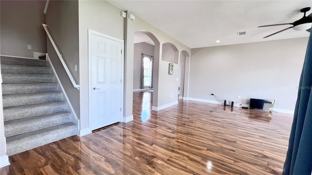 2012 Fern Ridge Ct, Holiday, FL 34691 - unfurnished living room with arched walkways, a ceiling fan, wood finished floors, stairs, and baseboards