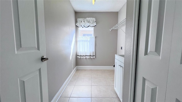 2012 Fern Ridge Ct, Holiday, FL 34691 - laundry room featuring cabinet space, a textured ceiling, electric dryer hookup, light tile patterned flooring, and baseboards