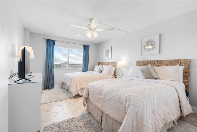 bedroom with ceiling fan, light tile patterned flooring, and a textured ceiling