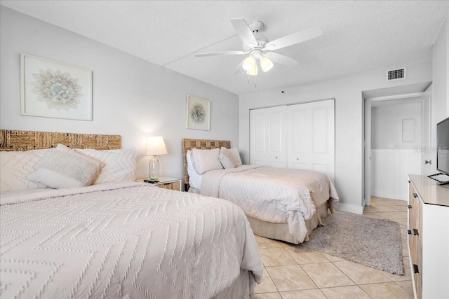 bedroom featuring light tile patterned floors, a textured ceiling, a closet, and ceiling fan