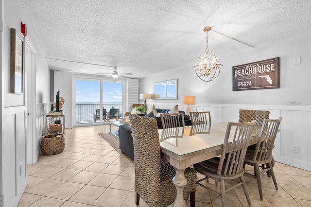 dining space with ceiling fan with notable chandelier, light tile patterned floors, and a textured ceiling