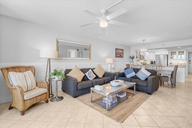 living room featuring a textured ceiling, ceiling fan, and light tile patterned flooring