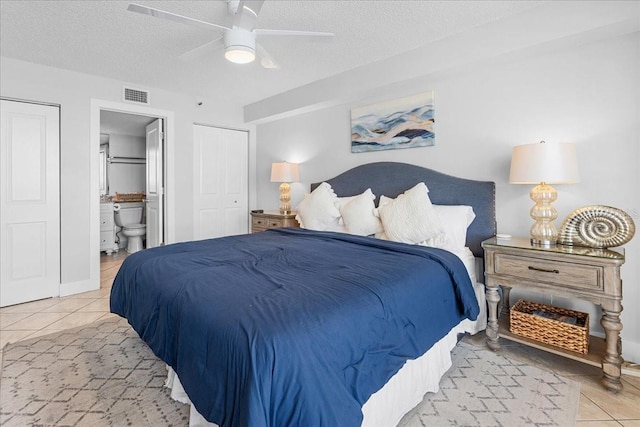 bedroom with ensuite bath, ceiling fan, light tile patterned flooring, and a textured ceiling