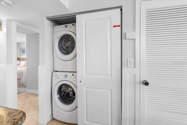 laundry room with light tile patterned floors and stacked washing maching and dryer