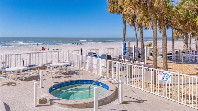 view of swimming pool with a beach view, a community hot tub, a patio, and a water view