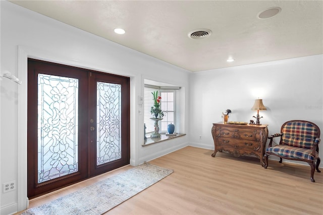 foyer entrance with french doors and light hardwood / wood-style floors