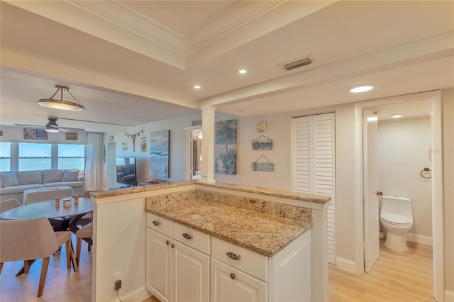 kitchen with light stone countertops, light wood-type flooring, ceiling fan, decorative light fixtures, and white cabinets