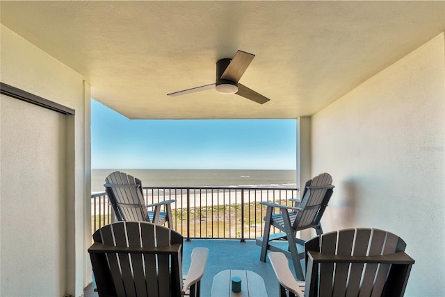 balcony featuring ceiling fan, a water view, and a view of the beach