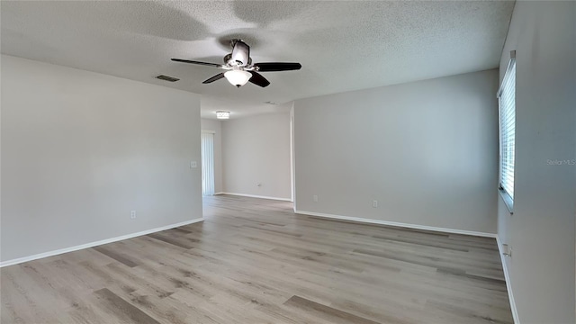 empty room featuring a textured ceiling, light hardwood / wood-style floors, and ceiling fan