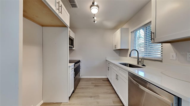 kitchen featuring light stone counters, stainless steel appliances, sink, light hardwood / wood-style floors, and white cabinetry