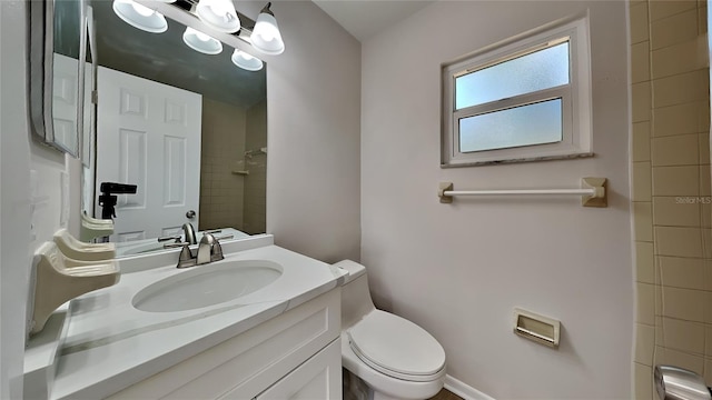 bathroom featuring vanity, toilet, and a tile shower