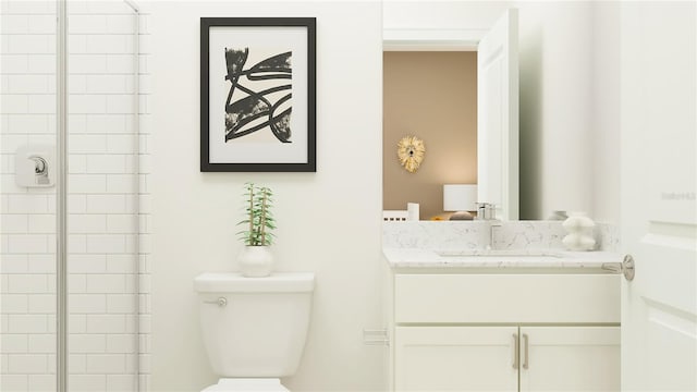 bathroom with tiled shower, vanity, and toilet