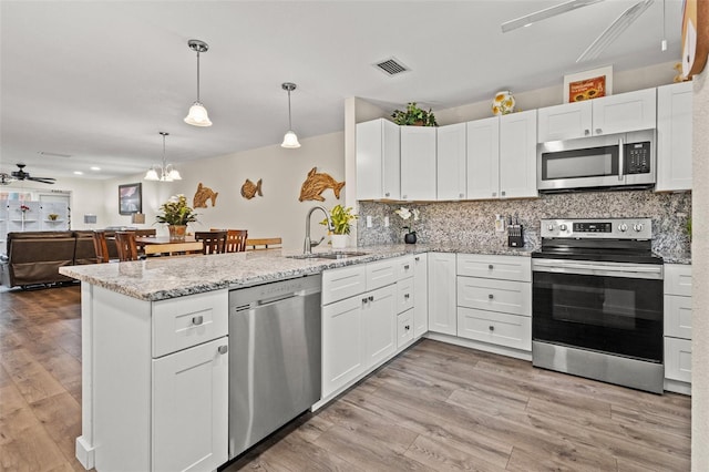 kitchen with ceiling fan with notable chandelier, sink, light wood-type flooring, appliances with stainless steel finishes, and white cabinetry