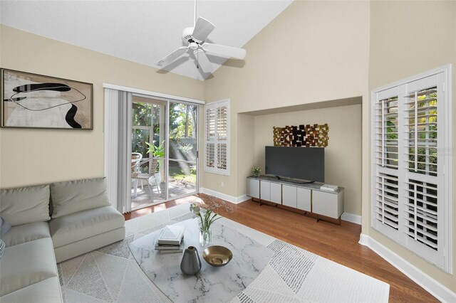 living room with ceiling fan, wood-type flooring, and high vaulted ceiling