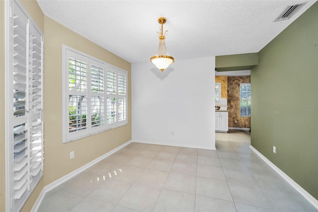 tiled empty room featuring a textured ceiling