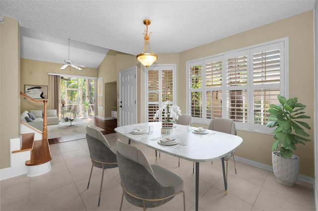 tiled dining space with a textured ceiling, ceiling fan, and vaulted ceiling