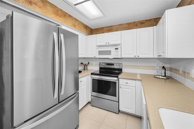 kitchen with white cabinets, light tile patterned floors, a textured ceiling, and stainless steel appliances