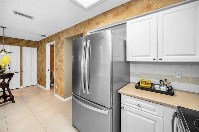 kitchen with stainless steel fridge, white cabinets, decorative light fixtures, and a textured ceiling