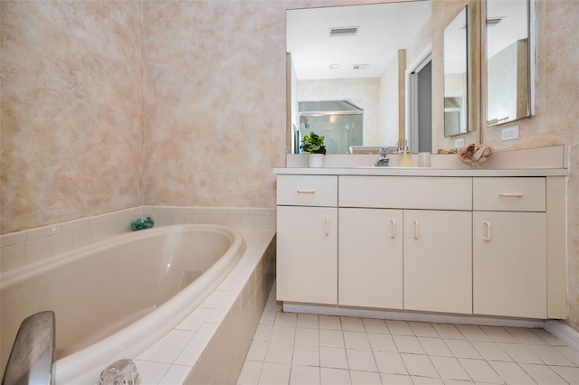 bathroom featuring tile patterned flooring, vanity, and tiled tub