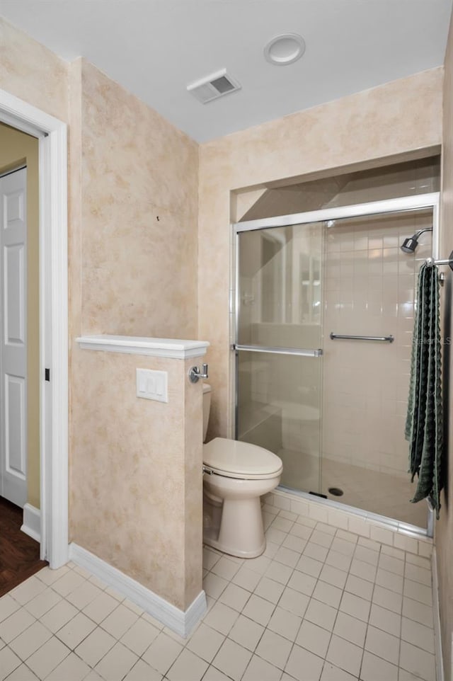 bathroom with toilet, tile patterned floors, and a shower with shower door