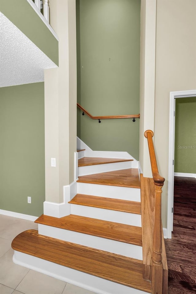 stairway with tile patterned flooring and a textured ceiling