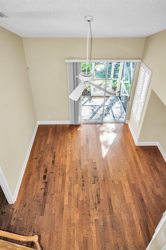 unfurnished dining area featuring wood-type flooring and a textured ceiling