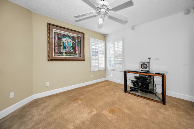 interior space featuring a textured ceiling, ceiling fan, and light carpet