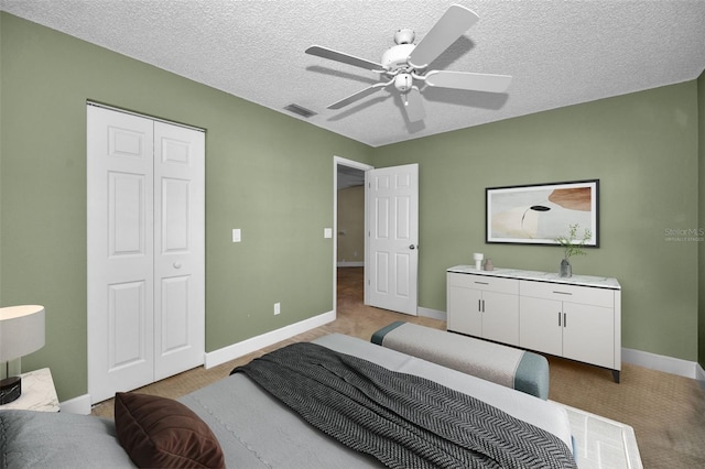 bedroom with ceiling fan, light carpet, and a textured ceiling