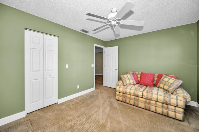 living area with carpet, ceiling fan, and a textured ceiling