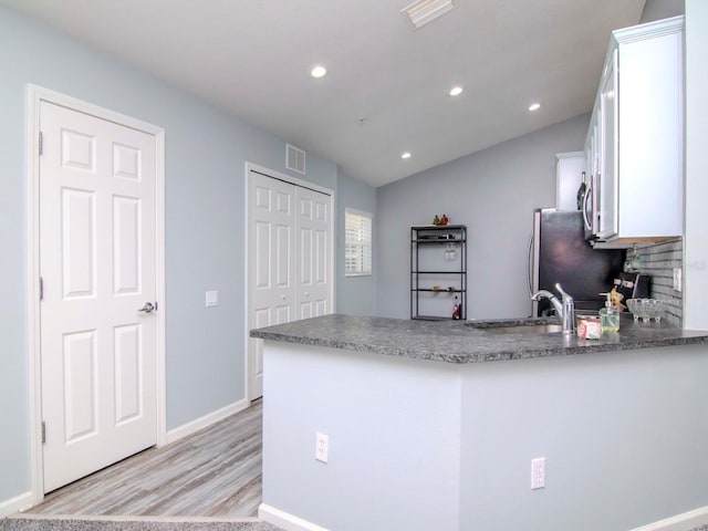 kitchen featuring lofted ceiling, white cabinets, double wall oven, light hardwood / wood-style flooring, and kitchen peninsula