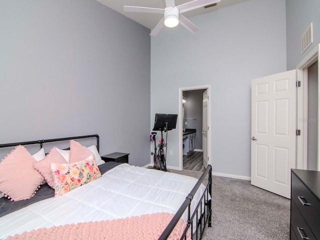 carpeted bedroom featuring connected bathroom, ceiling fan, and a towering ceiling