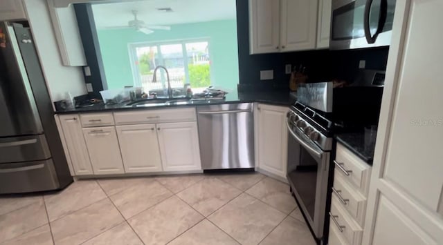 kitchen with white cabinets, stainless steel appliances, ceiling fan, and light tile patterned flooring